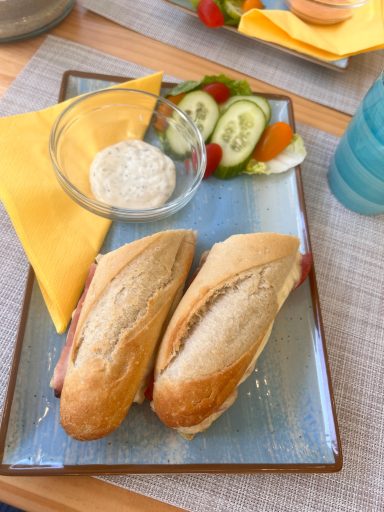 Zwei belegte Brötchen mit Gemüse und einer Schale mit Dip auf einem Teller.